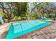 A screened pool with a unique statue and blue tile trim offers relaxation and artistic flair in a lush backyard setting at 4852 Peregrine Point N Cir, Sarasota, FL 34231