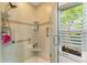 Bright and airy shower featuring tile surround, grab bars, and window view, offering safety and comfort at 4852 Peregrine Point N Cir, Sarasota, FL 34231