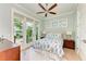 Light-filled bedroom with ceiling fan, wood floors, and access to a private balcony at 516 Kumquat Dr, Anna Maria, FL 34216