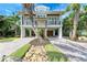 Stunning two-story coastal home featuring lush tropical landscaping and a brick paver driveway at 516 Kumquat Dr, Anna Maria, FL 34216
