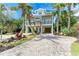 Beautiful two-story coastal home with balconies, mature landscaping, and brick paver driveway at 516 Kumquat Dr, Anna Maria, FL 34216