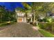 Charming home featuring a brick driveway, lush landscaping, a garage, and a welcoming entrance at 516 Kumquat Dr, Anna Maria, FL 34216