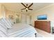 Well-lit main bedroom featuring hardwood floors, a ceiling fan, and a view of the ensuite bathroom at 516 Kumquat Dr, Anna Maria, FL 34216