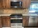 Modern stainless steel appliances, granite countertops, natural wood cabinets, and tile backsplash at 5438 Beneva Woods Way, Sarasota, FL 34233