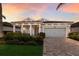 Charming home with a light blue facade, well-manicured landscaping, a two-car garage and a welcoming front porch at sunset at 5557 Long Shore Loop, Sarasota, FL 34238