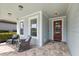 Inviting front porch with comfortable seating, brick flooring, and stylish exterior lighting at 5557 Long Shore Loop, Sarasota, FL 34238
