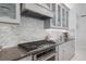 Modern kitchen with stainless steel appliances, gray cabinets and a marble tile backsplash at 5557 Long Shore Loop, Sarasota, FL 34238