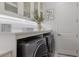 Bright laundry room featuring a gray washer and dryer, white cabinets and counter space, with modern decor and fixtures at 5557 Long Shore Loop, Sarasota, FL 34238