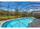 The screened-in pool area features a pristine pool, hot tub, and relaxing lounge chairs with a view of the garden at 5557 Long Shore Loop, Sarasota, FL 34238