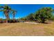 Large, fenced backyard with a concrete slab, mature trees, and grass, providing ample outdoor space at 5860 Brown Ln, Sarasota, FL 34232