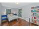 Cozy bedroom with tropical themed curtains, wood floors and unique bookshelf at 5860 Brown Ln, Sarasota, FL 34232