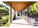 Covered walkway with wood floors leading to a home's interior, showing lush tropical landscape at 587 47Th St, Sarasota, FL 34234