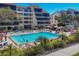 Stunning community pool with red umbrellas, lounge chairs, and beautiful palms at 6285 Midnight Pass Rd # 201, Sarasota, FL 34242