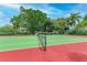 Well-maintained tennis court featuring a green and red surface, surrounded by lush greenery at 6342 Midnight Pass Rd # 212, Sarasota, FL 34242