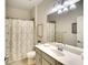 Functional bathroom featuring a single sink vanity with ample lighting and a shower-tub combination with patterned curtains at 6638 Willowshire Way, Bradenton, FL 34212