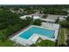 Aerial view of a large rectangular pool surrounded by trees, buildings, lounge chairs, and umbrellas at 6731 Northampton Pl, Bradenton, FL 34207