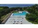 Aerial view of a pool with lounge chairs, umbrellas, tables, chairs, and manicured lawns surrounded by trees at 6731 Northampton Pl, Bradenton, FL 34207