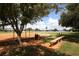 Community ball field with an orange clay surface, mature trees, and a wooden bench at 6731 Northampton Pl, Bradenton, FL 34207