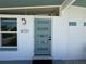 Modern white home featuring a stylish, teal-colored front door with glass panels, adjacent to a window at 6731 Northampton Pl, Bradenton, FL 34207