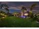Backyard view with green lawn and landscaping leading to a screened-in pool area at dusk at 7012 White Willow Ct, Sarasota, FL 34243
