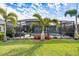 Beautiful backyard with a screened pool, tropical plants, and a lush green lawn at 7012 White Willow Ct, Sarasota, FL 34243