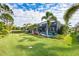 Expansive backyard with lush green grass, tropical landscaping, and a screened pool area at 7012 White Willow Ct, Sarasota, FL 34243