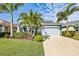 Charming single-story home boasts a two-car garage, a lush lawn with tropical landscaping, and a paver driveway at 7012 White Willow Ct, Sarasota, FL 34243