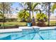 Close-up of the pool with tiled accents, lush greenery, and a view of the landscaped backyard at 7012 White Willow Ct, Sarasota, FL 34243