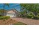 Charming home featuring a brick driveway, lush landscaping, and a well-manicured lawn under a bright, sunny sky at 7133 Victoria Cir, University Park, FL 34201