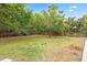 Spacious, fenced backyard featuring lush green grass and mature trees at 730 Rellim Ln, Sarasota, FL 34232