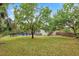 Large backyard with a well-maintained lawn, mature trees, and a fenced in pool at 730 Rellim Ln, Sarasota, FL 34232