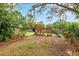 Backyard with a wooden playground set surrounded by mature landscaping and a fence at 730 Rellim Ln, Sarasota, FL 34232