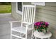 A white rocking chair and side table with flowers sit on a covered porch at 730 Rellim Ln, Sarasota, FL 34232