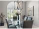Bright dining room with a glass table, leather chairs, elegant chandelier, and a large arched window at 7300 Wax Myrtle Way, Sarasota, FL 34241
