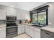 Bright kitchen boasts stainless steel appliances, white cabinets, and a large window overlooking the pool at 7300 Wax Myrtle Way, Sarasota, FL 34241