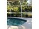 Pool with screened lanai overlooking serene green space with trees at 7300 Wax Myrtle Way, Sarasota, FL 34241