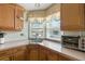 Well-lit kitchen sink area featuring wooden cabinetry, patterned wallpaper, and a window with backyard views at 772 Imperial Dr, North Port, FL 34287