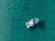 An aerial shot of a lone boat sailing in crystal-clear turquoise waters offering peace and solitude at 821 S Bay Blvd, Anna Maria, FL 34216