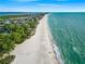 Expansive aerial view showcasing a long sandy beach meeting the clear turquoise ocean, offering a picturesque coastal lifestyle at 821 S Bay Blvd, Anna Maria, FL 34216