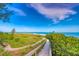 Tranquil beach view showing a wooden walkway leading to the beach with clear blue skies at 821 S Bay Blvd, Anna Maria, FL 34216