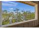 Stunning waterfront view of a dock framed by trees through the window at 821 S Bay Blvd, Anna Maria, FL 34216