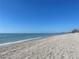 Beautiful sandy beach with clear blue water and a clear sky, perfect for relaxing and enjoying the coastal scenery at 8625 Midnight Pass Rd # 305B, Sarasota, FL 34242