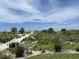 A sandy path surrounded by lush greenery, native plants, and palm trees leads to the tranquil, sandy beach at 8625 Midnight Pass Rd # 305B, Sarasota, FL 34242