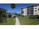 Exterior view of building with lush landscaping and a paved walkway leading to community amenities at 8625 Midnight Pass Rd # 305B, Siesta Key, FL 34242