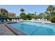 Community swimming pool area with lounge chairs, umbrellas, and lush tropical landscaping at 8625 Midnight Pass Rd # 305B, Siesta Key, FL 34242