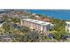 Aerial view of a multi-story condo complex surrounded by trees and overlooking the water at 8625 Midnight Pass Rd # 305B, Siesta Key, FL 34242