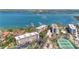 A picturesque aerial view of condo buildings, lush trees, and a bay with various boats, tennis courts, and residential buildings at 8625 Midnight Pass Rd # 305B, Siesta Key, FL 34242