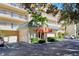 Exterior view of the building's entrance with a covered awning and well-maintained landscaping at 8625 Midnight Pass Rd # 305B, Siesta Key, FL 34242