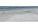 Expansive aerial view of the beach, highlighting the sandy shore, ocean waves, and scattered beachgoers and umbrellas at 1239 Siesta Bayside Dr # 1239C, Sarasota, FL 34242