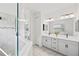 Modern bathroom with a glass-enclosed shower, double vanity with white cabinets, and marble-tiled floors at 12959 Seasong Ter, Bradenton, FL 34211